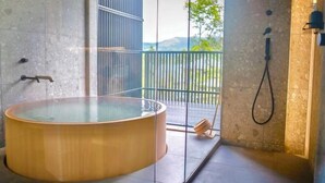 Un bagno moderno con una grande vasca da bagno in legno, box doccia in vetro e vista sull'esterno.