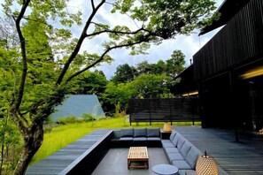 Un espace extérieur moderne aménagé avec une table et des bancs en bois, entouré de verdure et d’une structure architecturale.