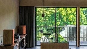 Un interno moderno con un tavolo in vetro, mobili in legno e un balcone con vista sugli alberi.