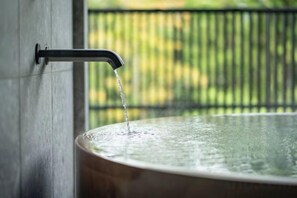 A water spout with water flowing into a large, round container. - MONS GORA (Hakone)