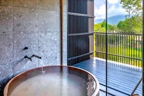 Wellnessbereich mit Whirlpool, Steinwand und Gartenblick durch eine Glastür.