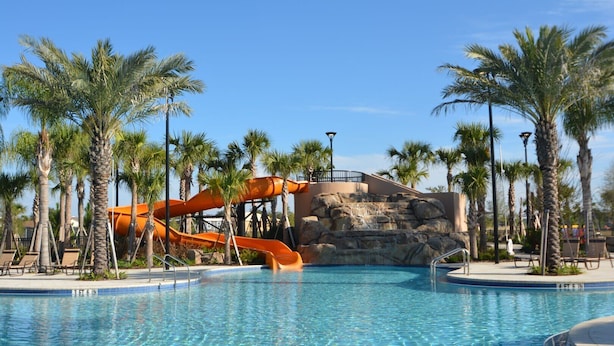 A swimming pool with a water slide and palm trees. - Lovely Home in Gated Resort with Extensive Amenities (Davenport)