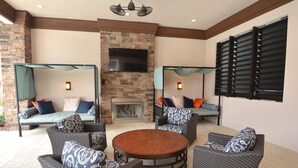 A patio area with wicker furniture, a round wooden table, and a stone fireplace. - Lovely Home in Gated Resort with Extensive Amenities (Davenport)