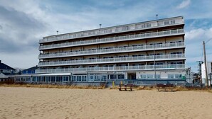 Ein mehrstöckiges Hotel mit Balkonen, direkt an einem Sandstrand gelegen.