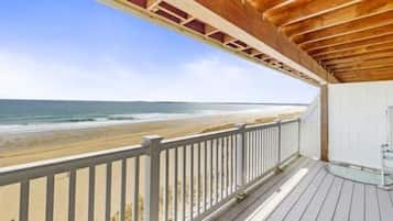 A wooden deck with a railing overlooking a beach.