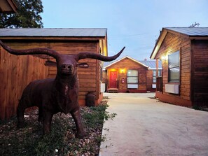 Un bâtiment rustique, avec une grande statue de taureau devant, un revêtement extérieur en bois et une porte rouge.