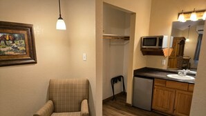 Une petite pièce agréable et chaleureuse, avec un fauteuil à motifs écossais, une kitchenette compacte dotée d’un four à micro-ondes et un plancher en bois.
