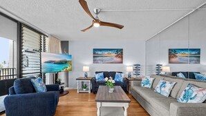Ein modernes Wohnzimmer mit Deckenventilator, zwei Sofas, einem Couchtisch und Kunstwerken an den Wänden.