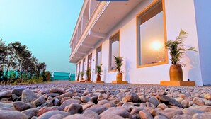 A building with a white facade, large windows, and potted plants. - Foreste Resort (Ramnagar)