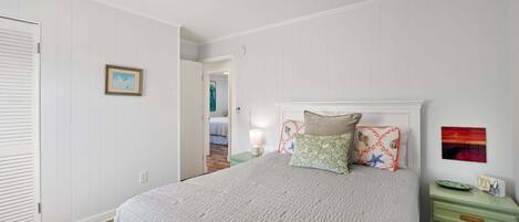Ein Schlafzimmer mit einem Bett, einem Nachttisch, einer Kommode und einer Tür.