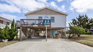 A two-story building with a balcony, a sign indicating a vacation rental, and a wooden deck. - Little Island Time: Walk to Beach Retreat (Kitty Hawk)