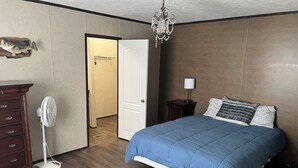 Un dormitorio con cama, cómoda, ventilador y candelabro.