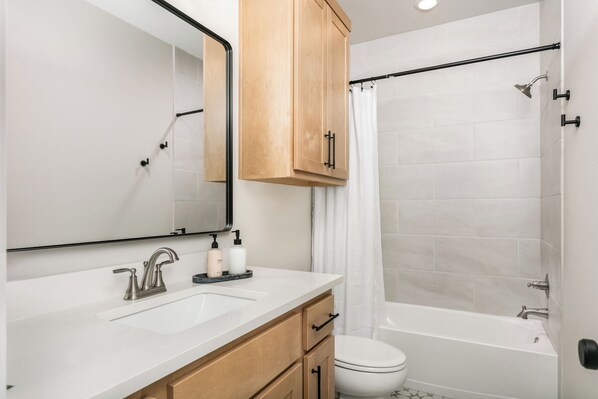 A modern bathroom with a double sink, a toilet, and a bathtub.