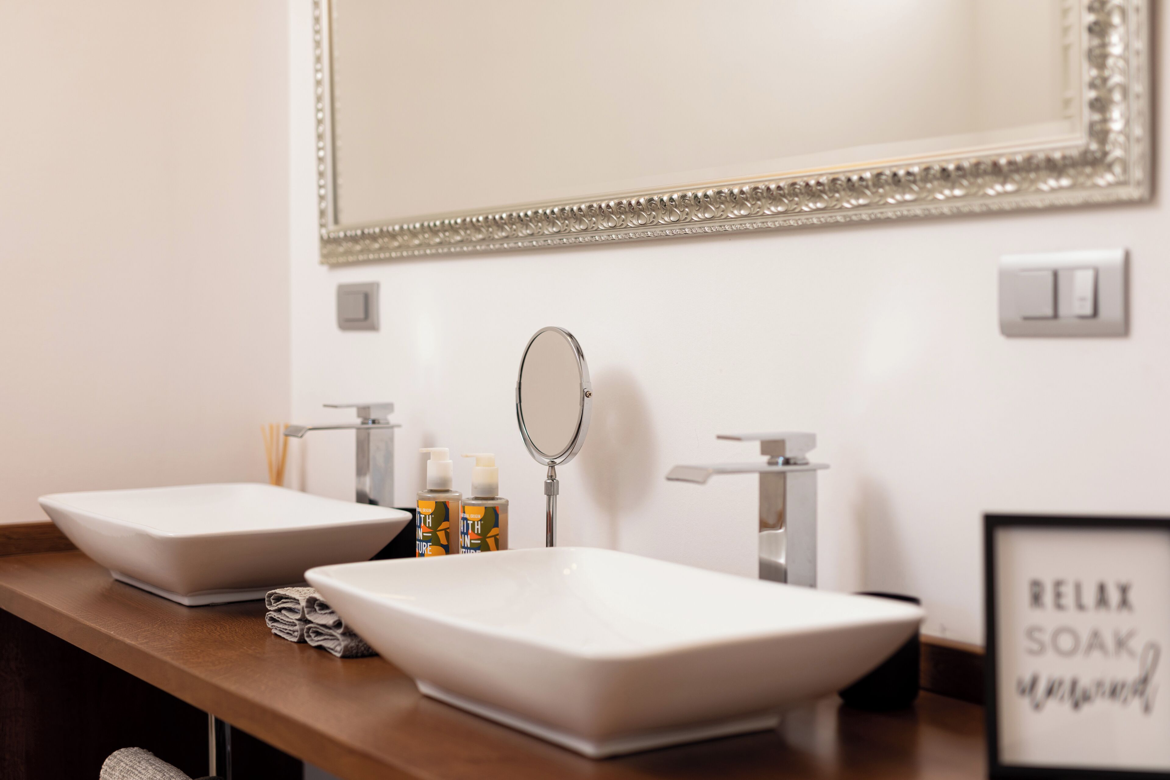 A bathroom with two sinks, a mirror, and toiletries.
