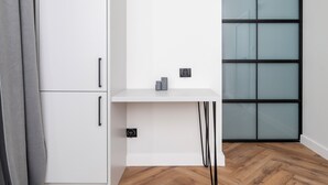 A white desk with two electrical outlets, a grey curtain, and a wooden floor. - Piotrkowska Grand Avenue Apartment #C (Łódź)