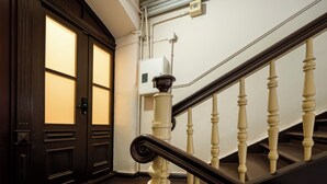A staircase with a black handrail and white balusters, leading to a dark wooden door with glass panels.