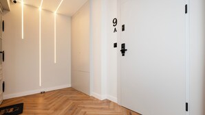 A hallway with wooden flooring, white walls, and a door marked with the number 9A.