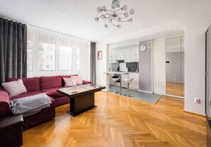 A modern living room with a sofa, a coffee table, and a dining area with a kitchen in the background. - Warszawa Wola Homely Apartment (Warszawa)