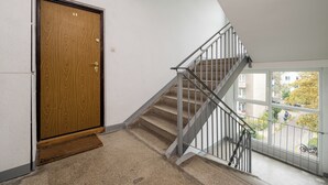 A staircase with a metal railing leading to an upper floor. A wooden door with a number 11 is visible on the left. - Warszawa Wola Homely Apartment (Warszawa)