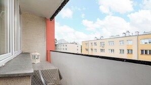 A balcony with a view of neighboring buildings, a small table with a patterned tablecloth, and a white lantern. - Warszawa Wola Homely Apartment (Warszawa)