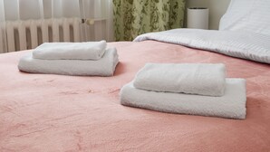 A neatly made bed with pink bedding and two folded white towels. - Warszawa Wola Homely Apartment (Warszawa)