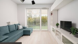 A modern living room with a teal sofa, a flat-screen TV, and a white entertainment unit.