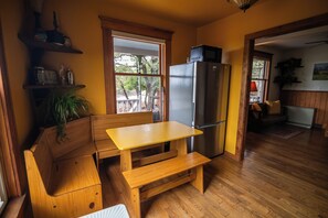 A compact kitchen with a built-in refrigerator, wooden bench seating, and a window overlooking a garden.