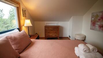 A bedroom with a bed, a wooden dresser, a nightstand, and a lamp.
