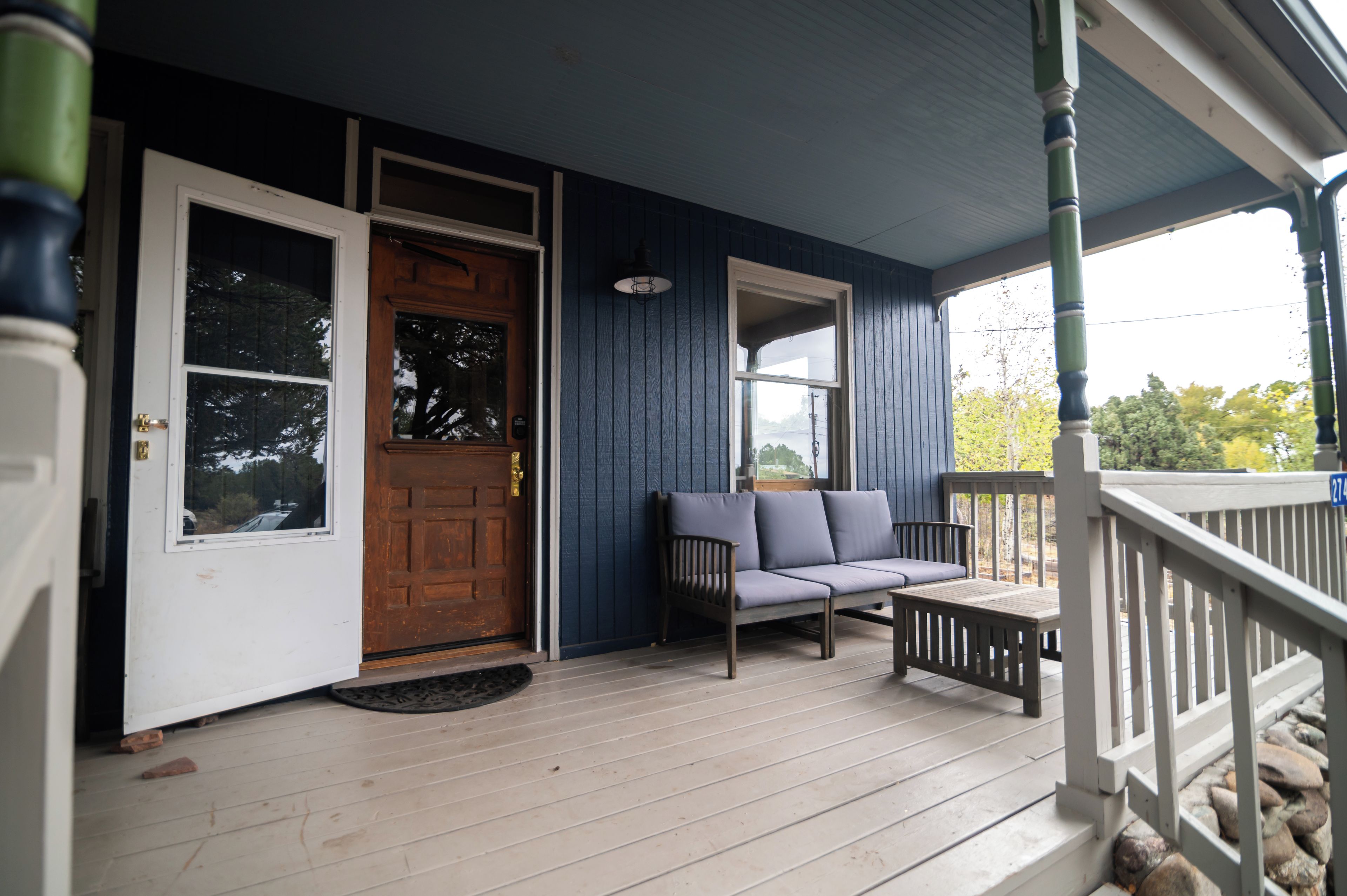 A porch with a wooden door, a bench, and a table.