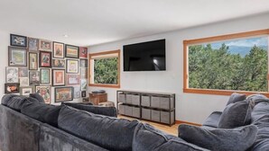 Ein modernes Wohnzimmer mit einem großen Ecksofa, einem flachbildfernseher an der Wand und einer Sammlung gerahmter Bilder.