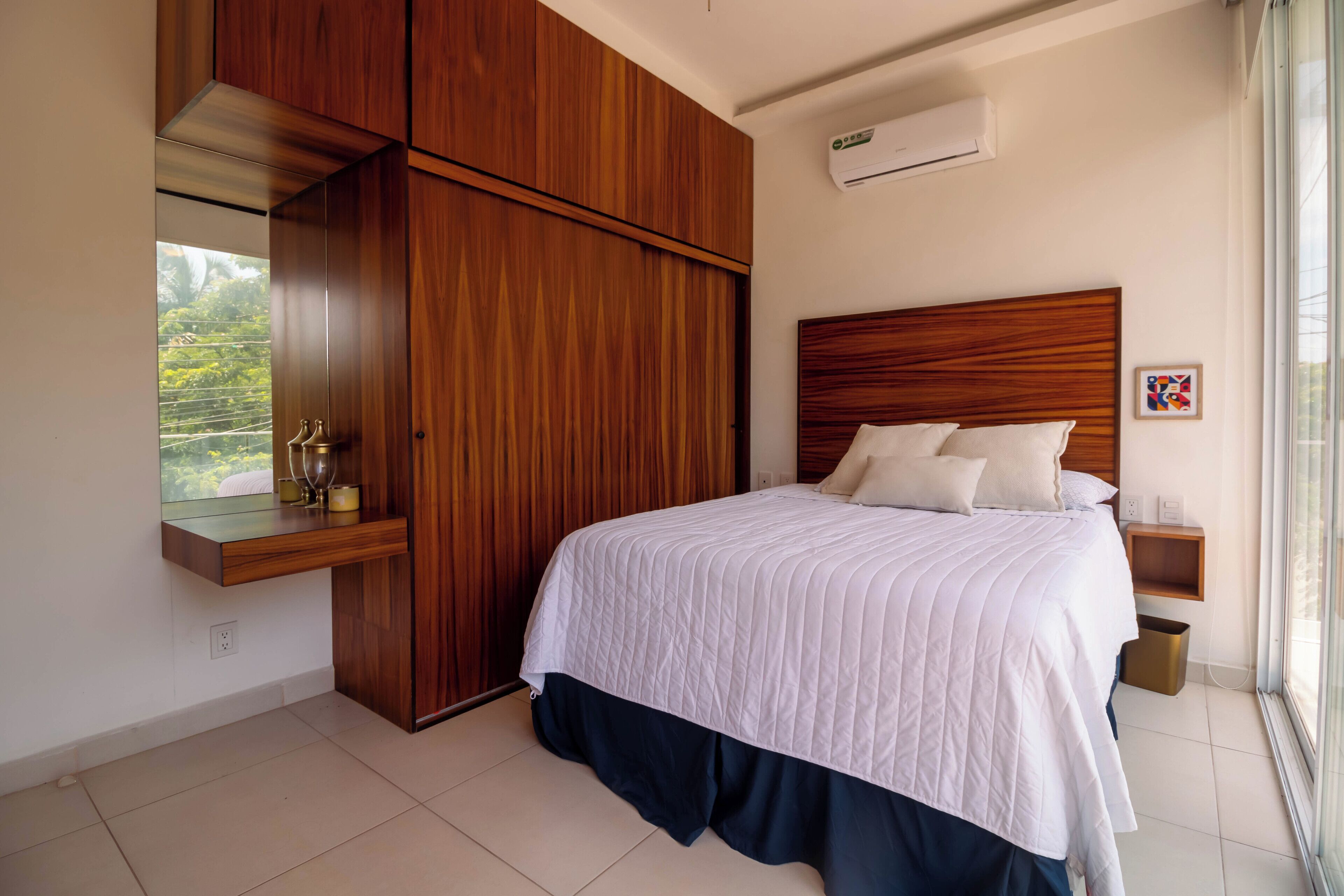 Une chambre avec un grand lit, une armoire en bois et une petite table de chevet.