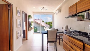 A modern kitchen with a dining area, large windows, and a view of the outside.