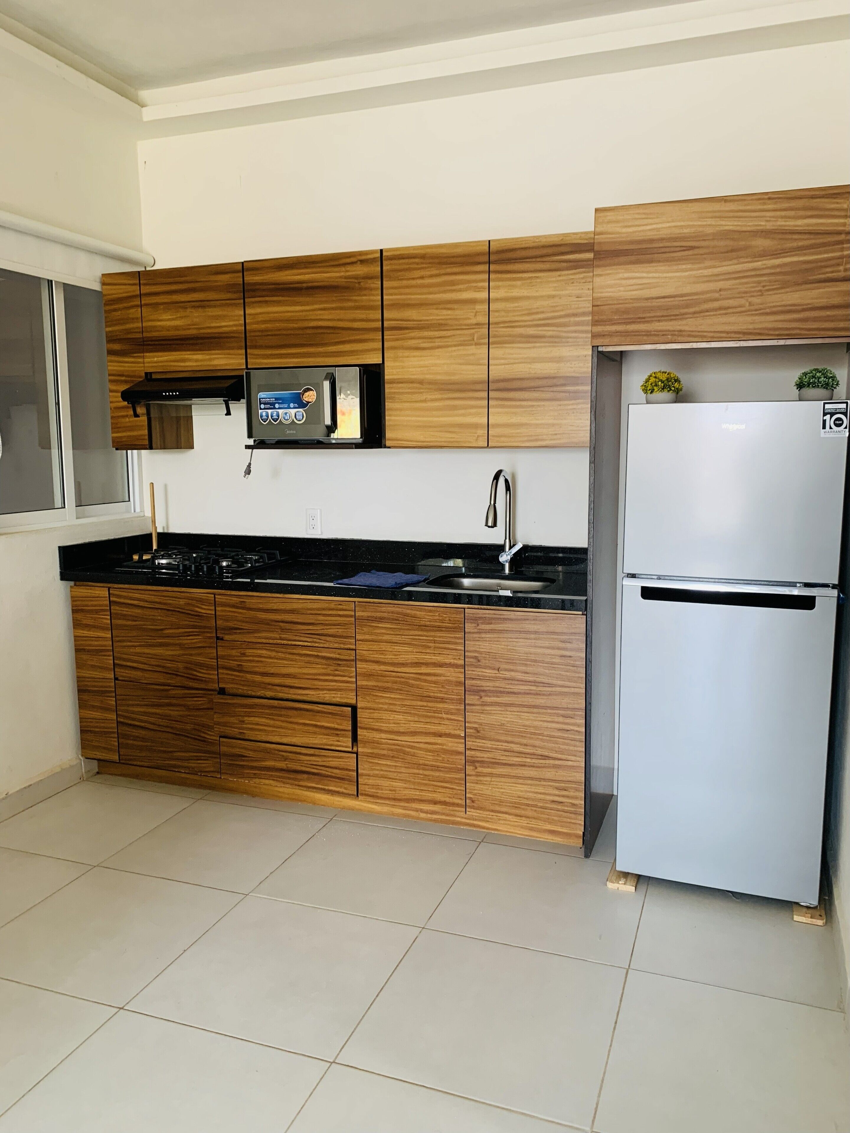 Een moderne keuken met houten kasten, een ingebouwde magnetron, een roestvrijstalen koelkast en een gasfornuis.