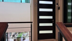 A black door with white horizontal stripes, a number '5' above it, and a small mailbox to the right. - Steps from 5th Ave, 2 Bedroom Luxury Condo, 2 Baths, 4 min to Beach,Rooftop Pool (Playa del Carmen)