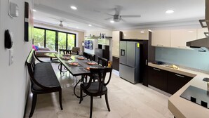 A modern kitchen with a dining area, large windows, and a ceiling fan. - Steps from 5th Ave, 2 Bedroom Luxury Condo, 2 Baths, 4 min to Beach,Rooftop Pool (Playa del Carmen)