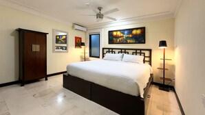 A bedroom with a bed, a ceiling fan, a nightstand, a lamp, and artwork on the walls. - Steps from 5th Ave, 2 Bedroom Luxury Condo, 2 Baths, 4 min to Beach,Rooftop Pool (Playa del Carmen)