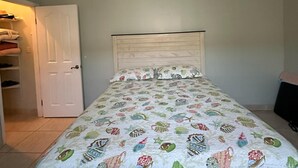 Una camera da letto con un letto, una ventola a soffitto e una porta.