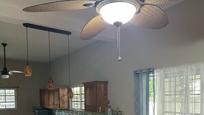 Un'ampia cucina con isola centrale, sedie in legno e una ventola a soffitto.