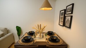 A dining area with a table set for four, featuring black bowls and plates, a vase with dried reeds, and a hanging lamp. - CASA BOHO I Cozy Boho Retreat in NW Calgary (Calgary)