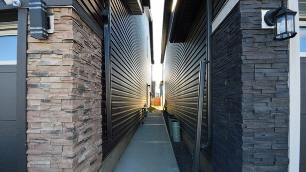 A narrow, covered walkway with stone walls and metal shutters, leading to a building entrance. - CASA BOHO I Cozy Boho Retreat in NW Calgary (Calgary)