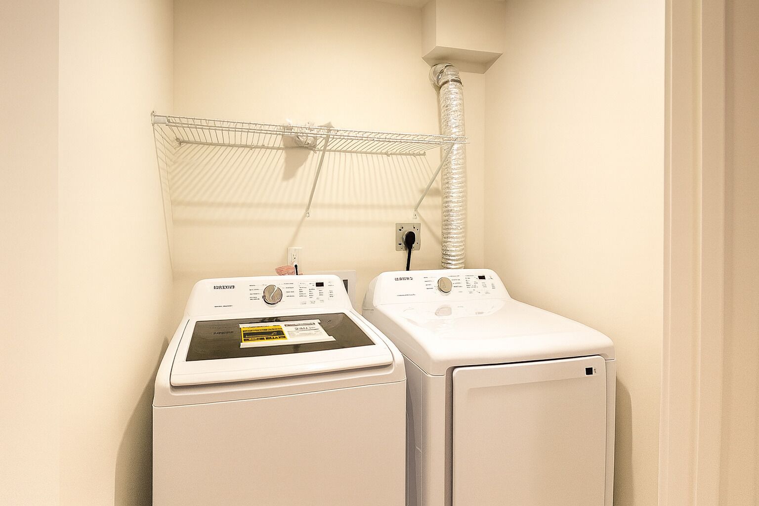 A laundry room with two white washing machines and a drying rack.