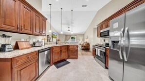 A modern kitchen with wooden cabinets, stainless steel appliances, granite countertops, and a central island. - Modern Getaway-Private Tub & Game Room (Ocala)