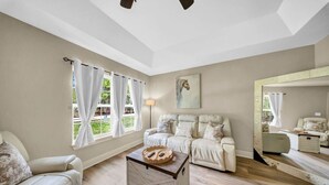 A spacious living room with a large sofa, a coffee table, and a mirror. - Modern Getaway-Private Tub & Game Room (Ocala)