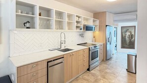 Une cuisine moderne avec un dosseret de carreaux disposés en motif chevron, des appareils en acier inoxydable et des étagères intégrées.