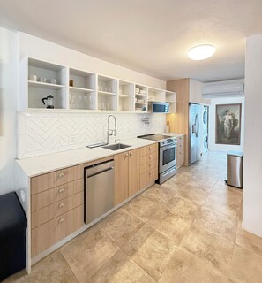 Een moderne keuken met een backsplash van visgraat tegels, roestvrijstalen apparatuur en ingebouwde planken.