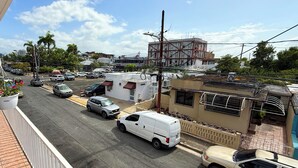 Une vue de rue avec des voitures garées, un fourgon blanc et un bâtiment en construction.