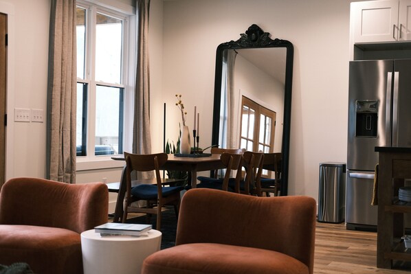 A modern dining area with a round table, chairs, and a large mirror.