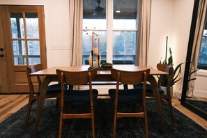 Un coin repas avec une table et des chaises en bois, un vase contenant des branches et une plante en pot.
