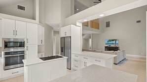 A modern kitchen with white cabinetry, stainless steel appliances, and a central island. - Stunning pool home steps to beach! REDUCED! (Sanibel)