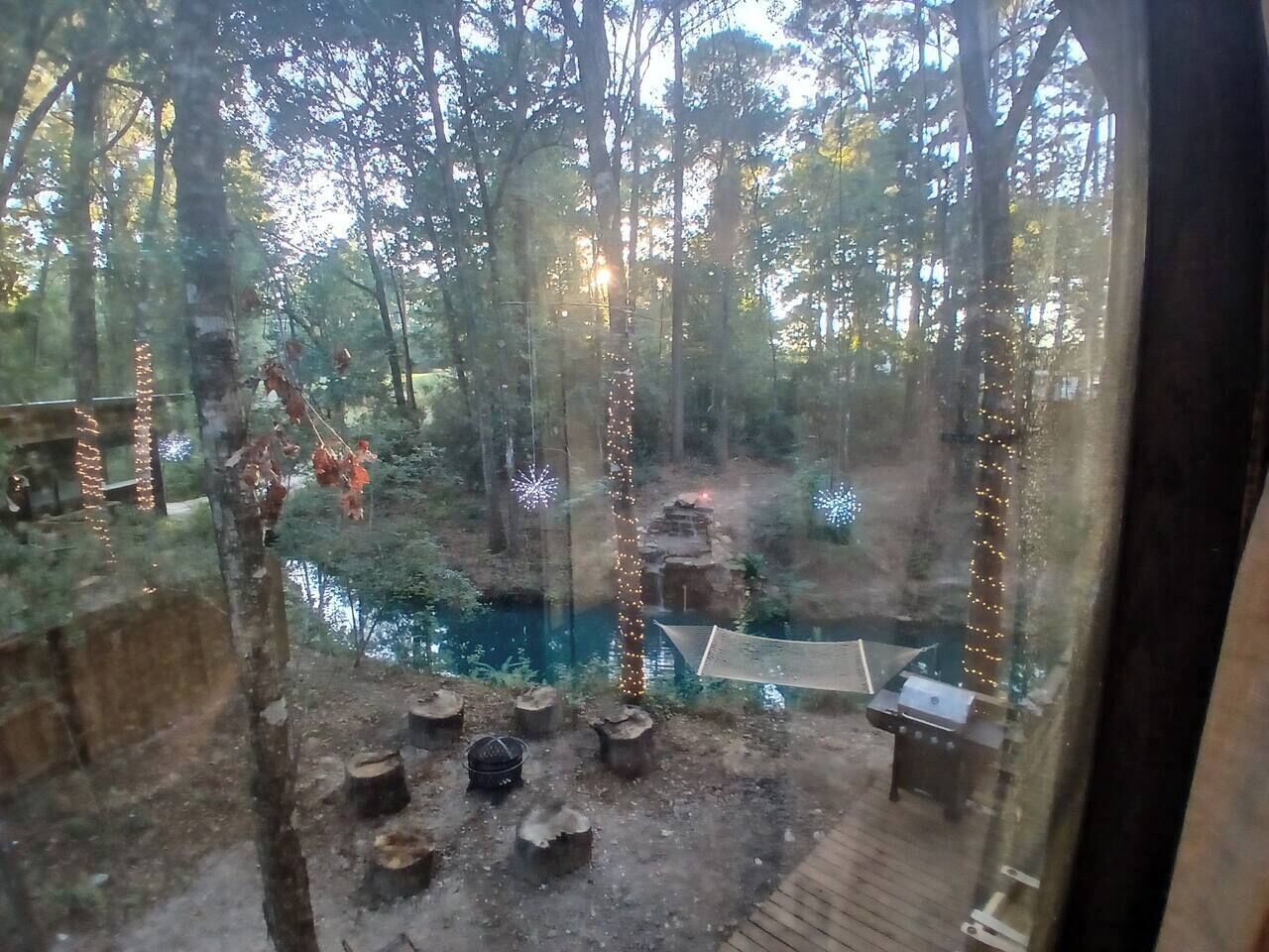 En vy över ett skogsområde med en flod, träkonstruktioner och ljusslingor.